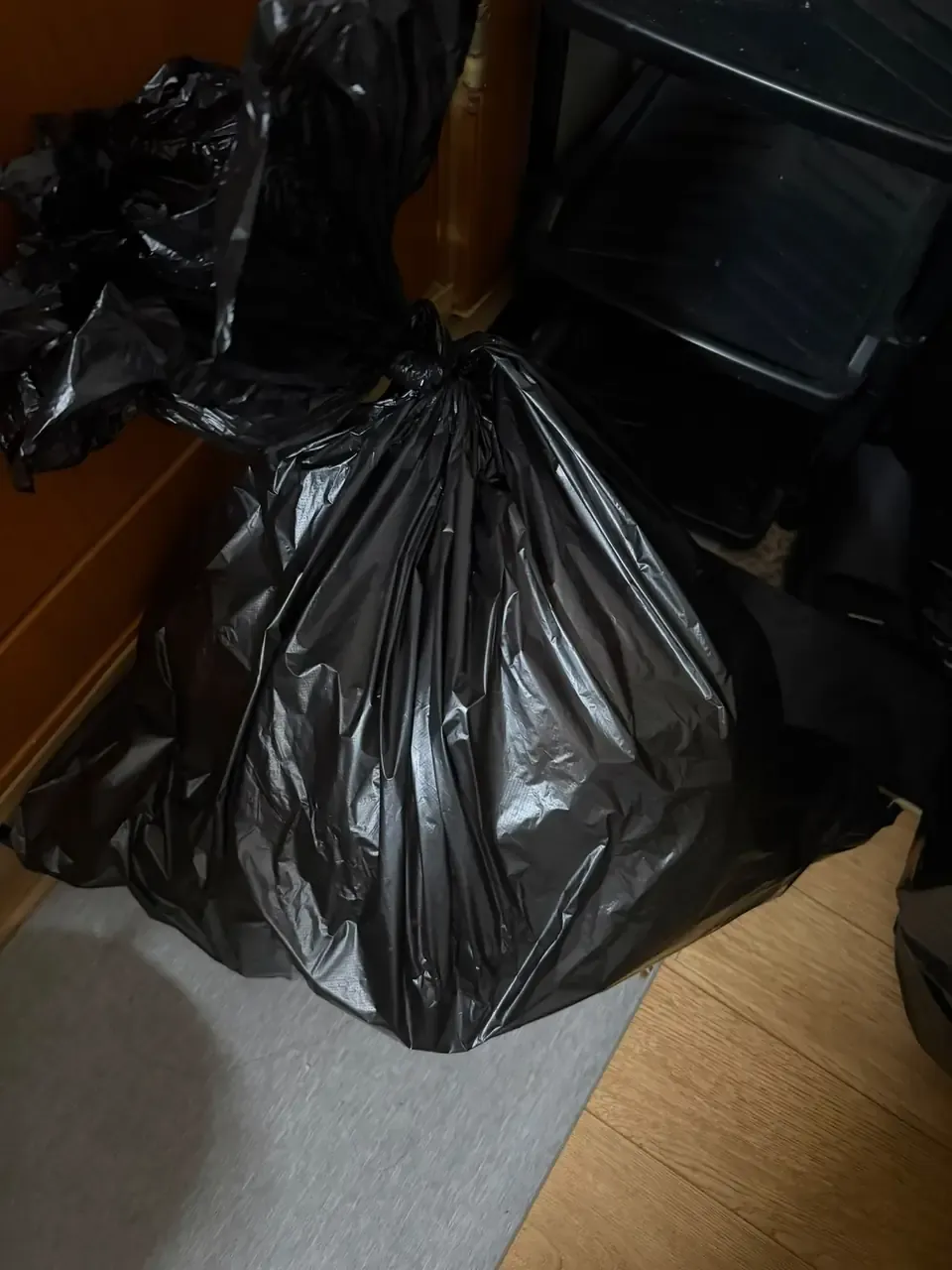 Several tied black rubbish bags lined up along the wall of a small Korean flat