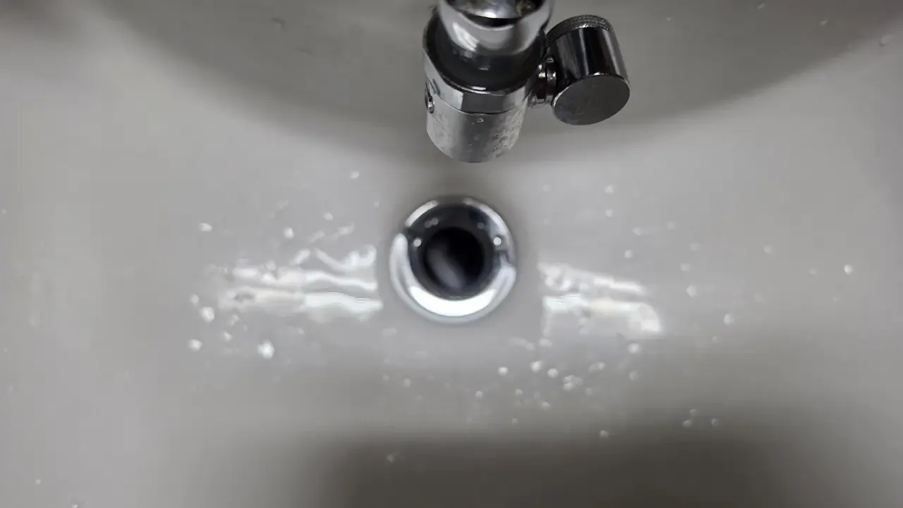 Water running freely down a clean bathroom basin drain
