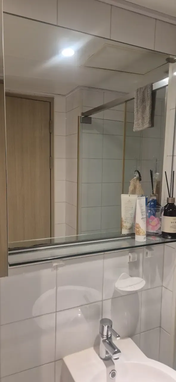 A washbasin with a wide mirror and glass shelf after cleaning