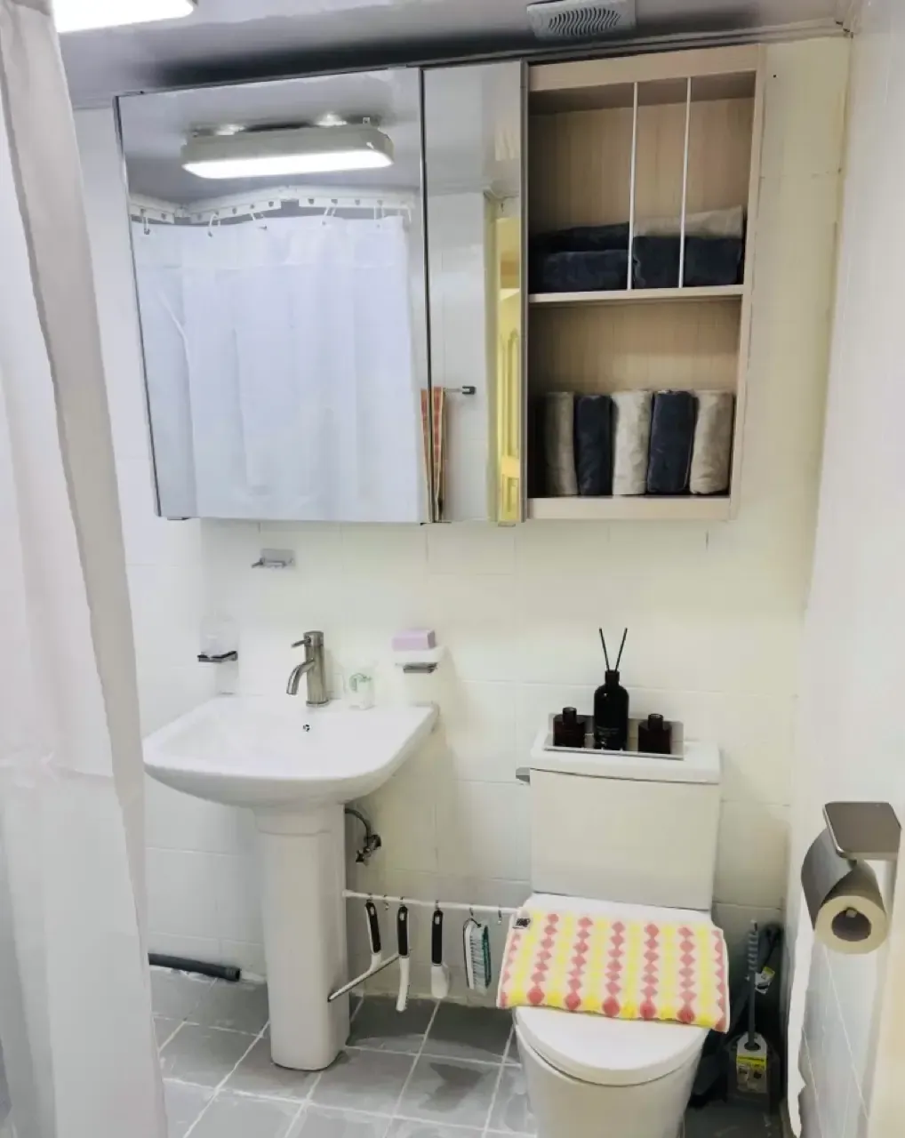 A compact bathroom with a basin, toilet and mirror cabinet
