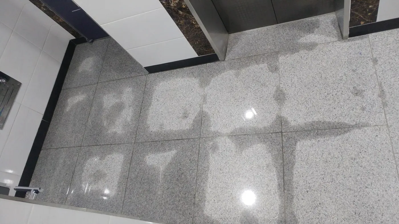 Water spreading across the granite floor of an apartment lobby by the lift