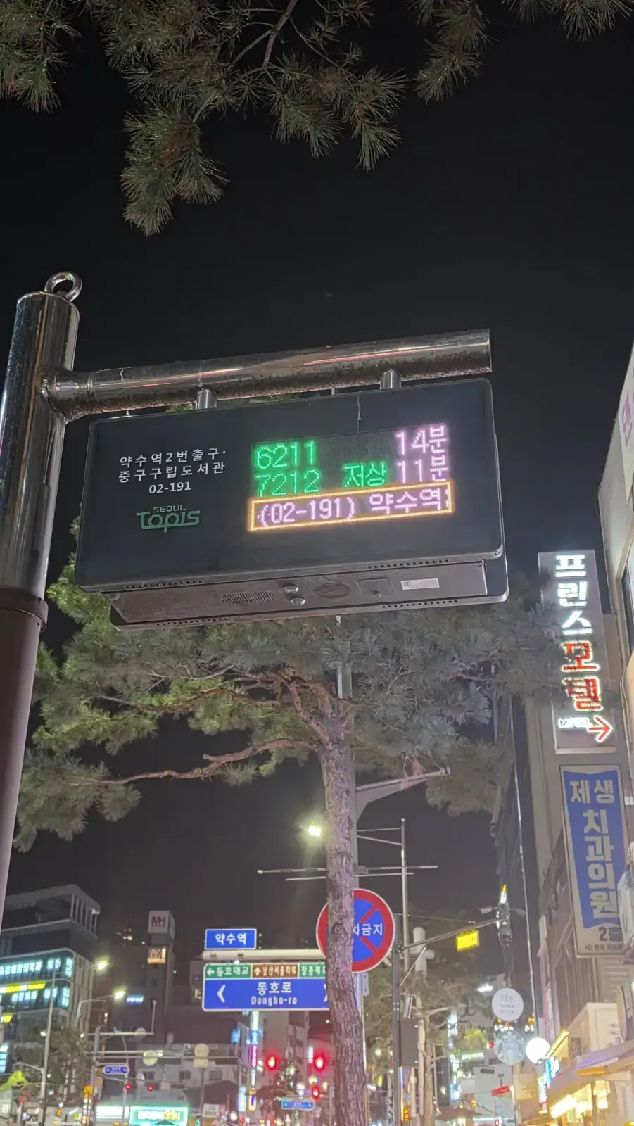 A Seoul bus stop LED display at night showing bus numbers and arrival times in minutes