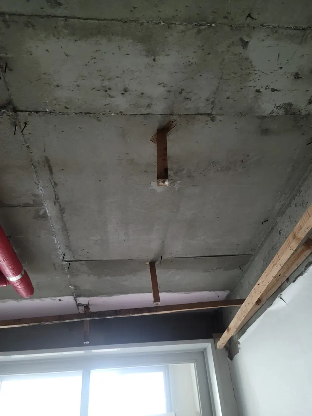 A ceiling and wall stripped back to bare concrete slab with timber battens remaining