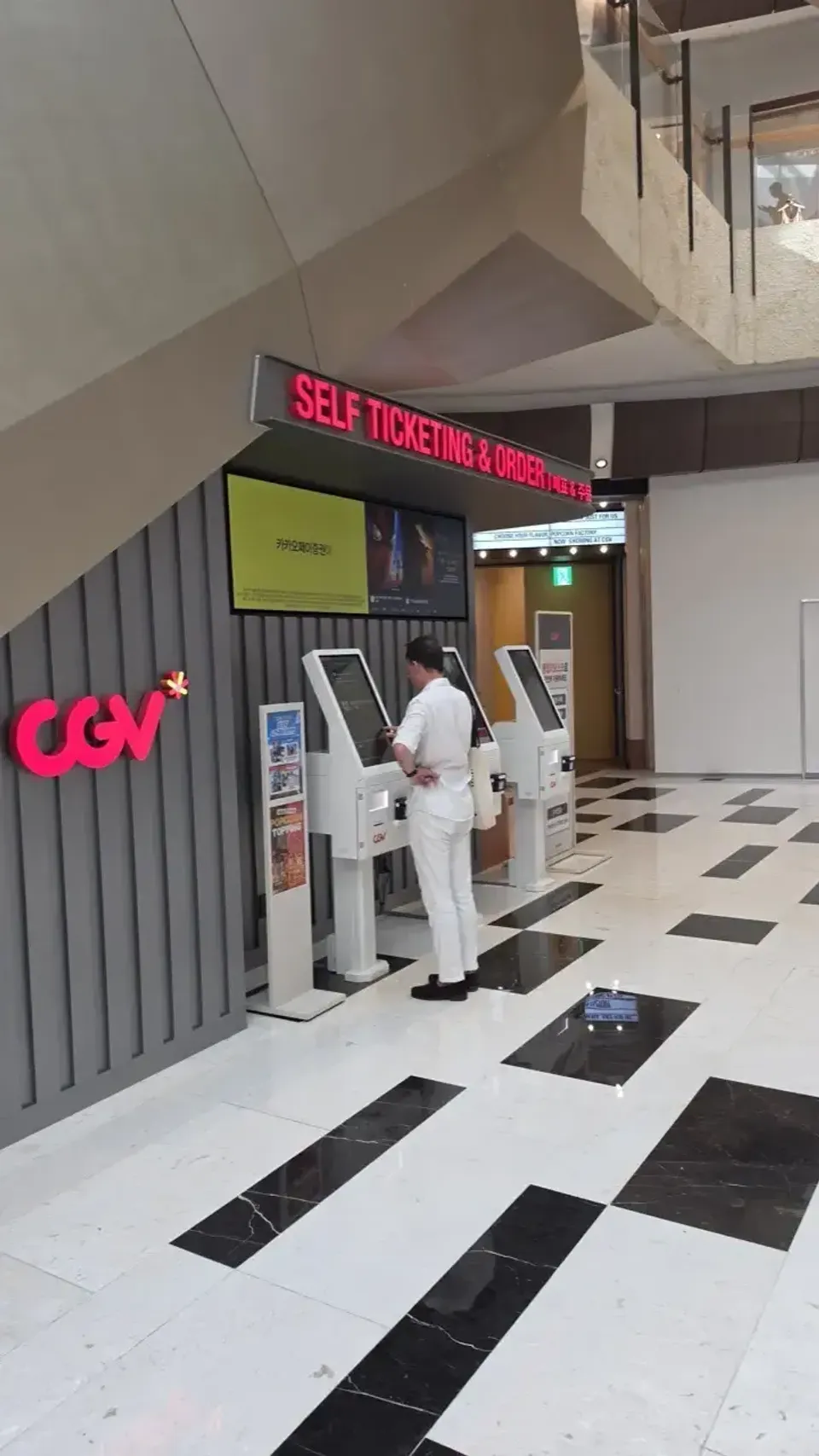 A foreigner using a self-ticketing kiosk under the CGV sign at the newly reopened CGV Yeouido in IFC Mall, Seoul