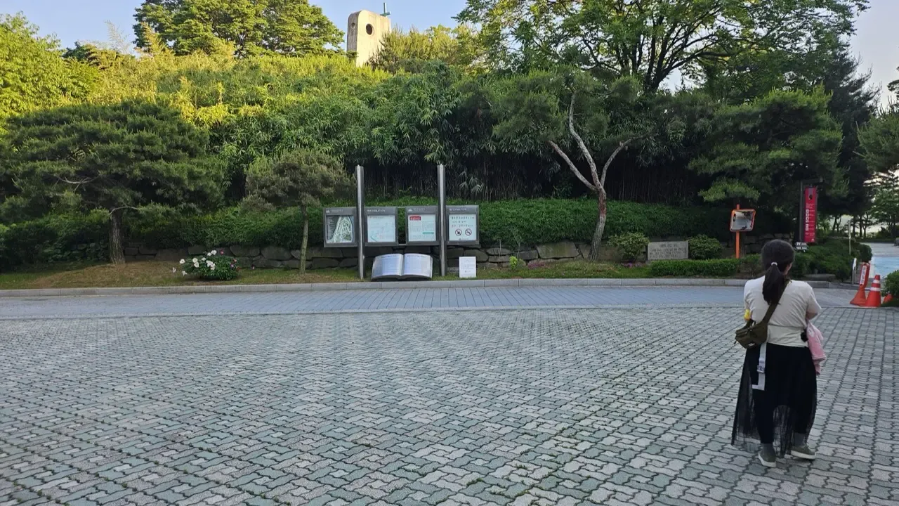 A wide, spotlessly clean paved plaza at a Seoul park entrance with no litter and no bins in sight