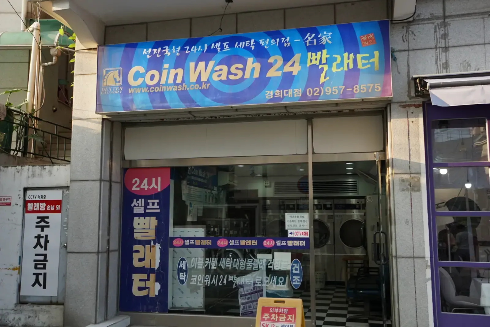 A 24-hour self-service coin laundry storefront with washing machines visible inside