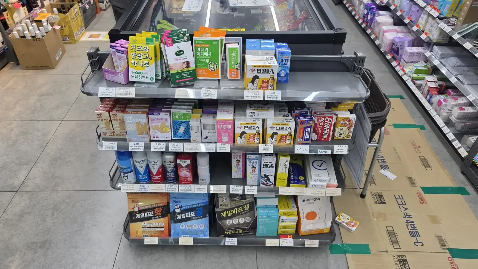 A convenience store health aisle with adhesive plasters, medicated patches, masks and first aid items