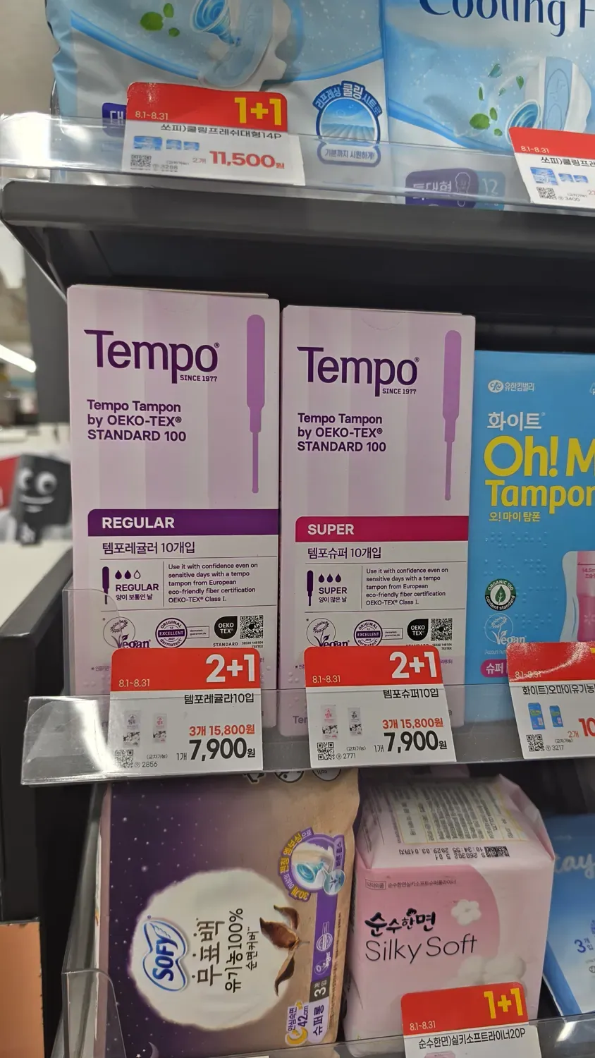 A convenience store shelf holding boxes of Tempo tampons in Regular and Super, with 2+1 promotion tags showing 7,900 won each