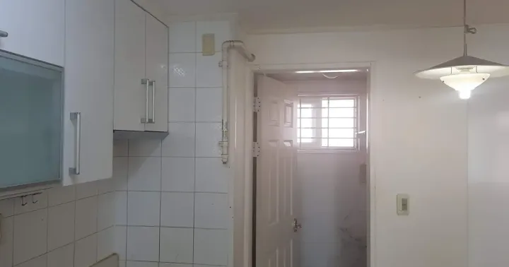 An empty Korean kitchen at handover, with the utility room door open behind it showing a mould-stained wall