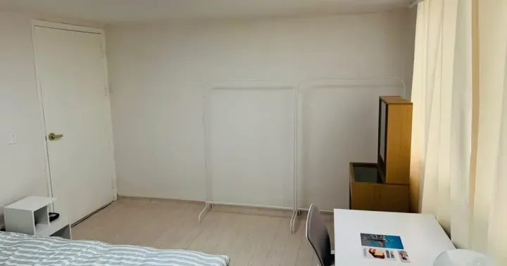 A single room in a Seoul share house with a bed, desk, wardrobe rail and window