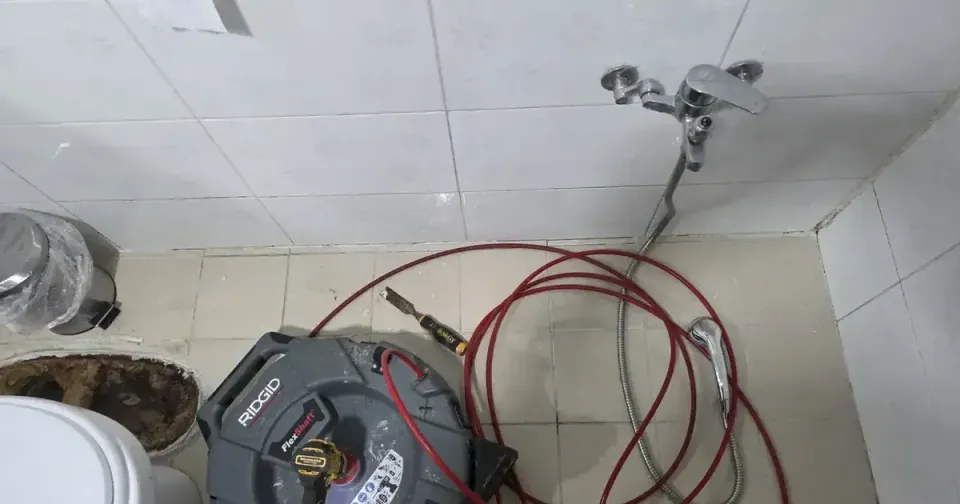 A RIDGID FlexShaft drain machine on a Korean bathroom floor, red cable coiled beside it, the toilet lifted off its flange in the corner