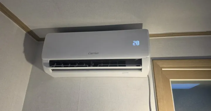 A wall air conditioner running with its vent open, the interior louvres visible
