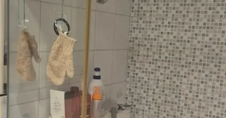 A cleaned Korean shower area with white tiles, mosaic feature wall and a linear floor drain
