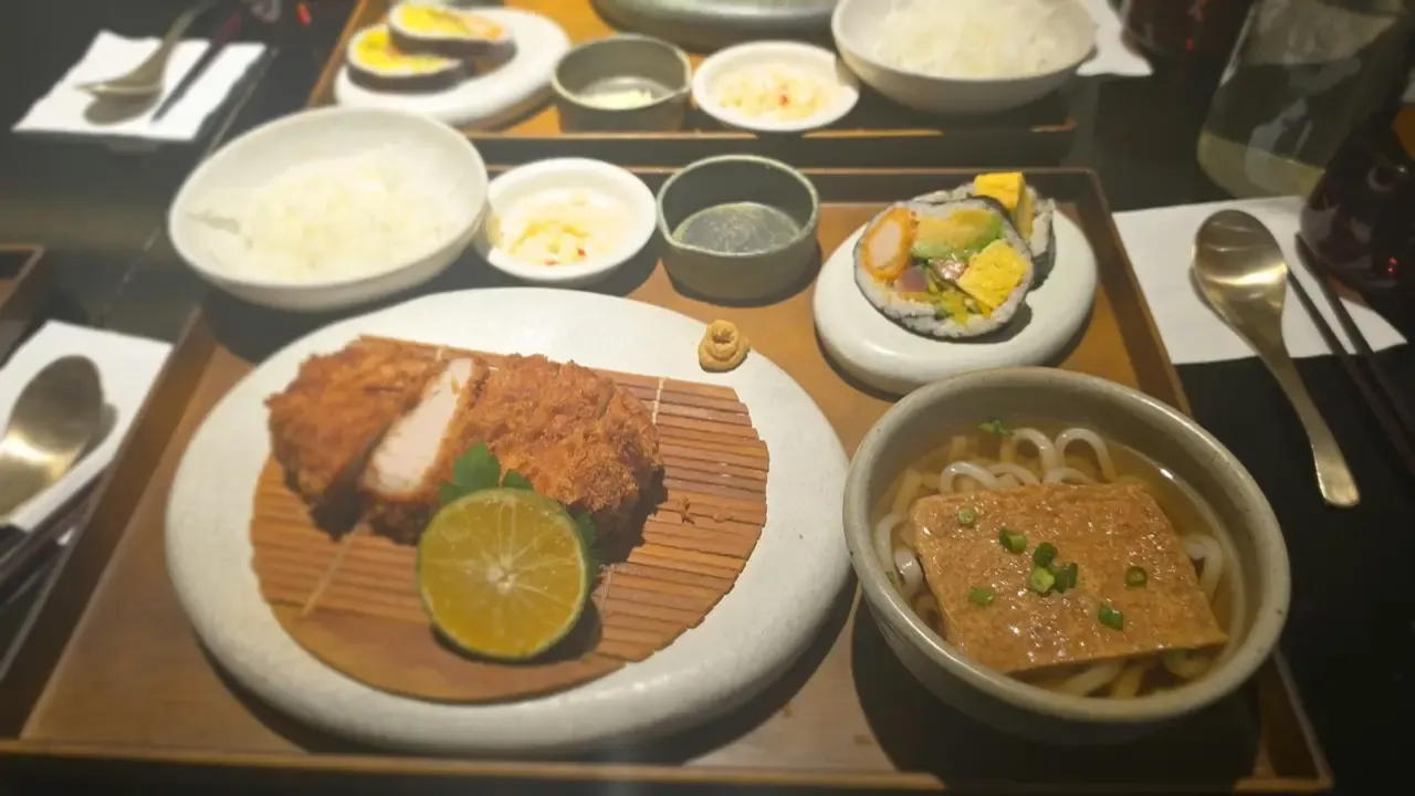 A Korean set meal on a wooden tray with rice, soup, side dishes and cutlery