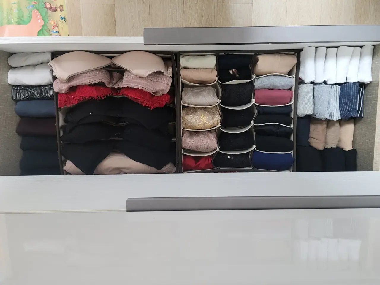 A drawer after organising, with socks and underwear rolled into individual cells of fabric divider trays