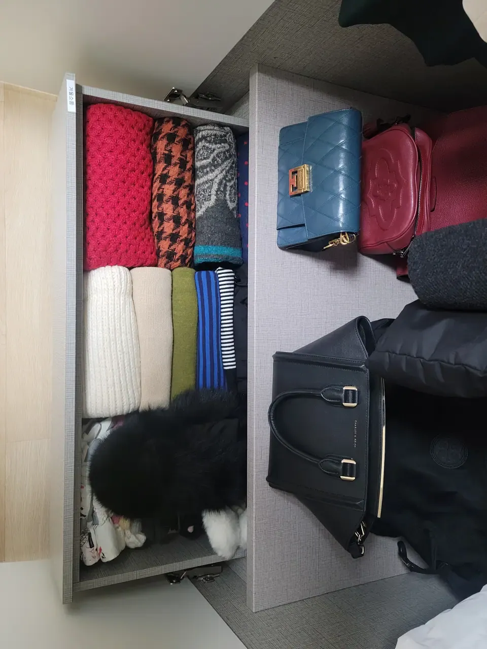 A drawer of winter accessories after organising, with a printed label on the drawer front