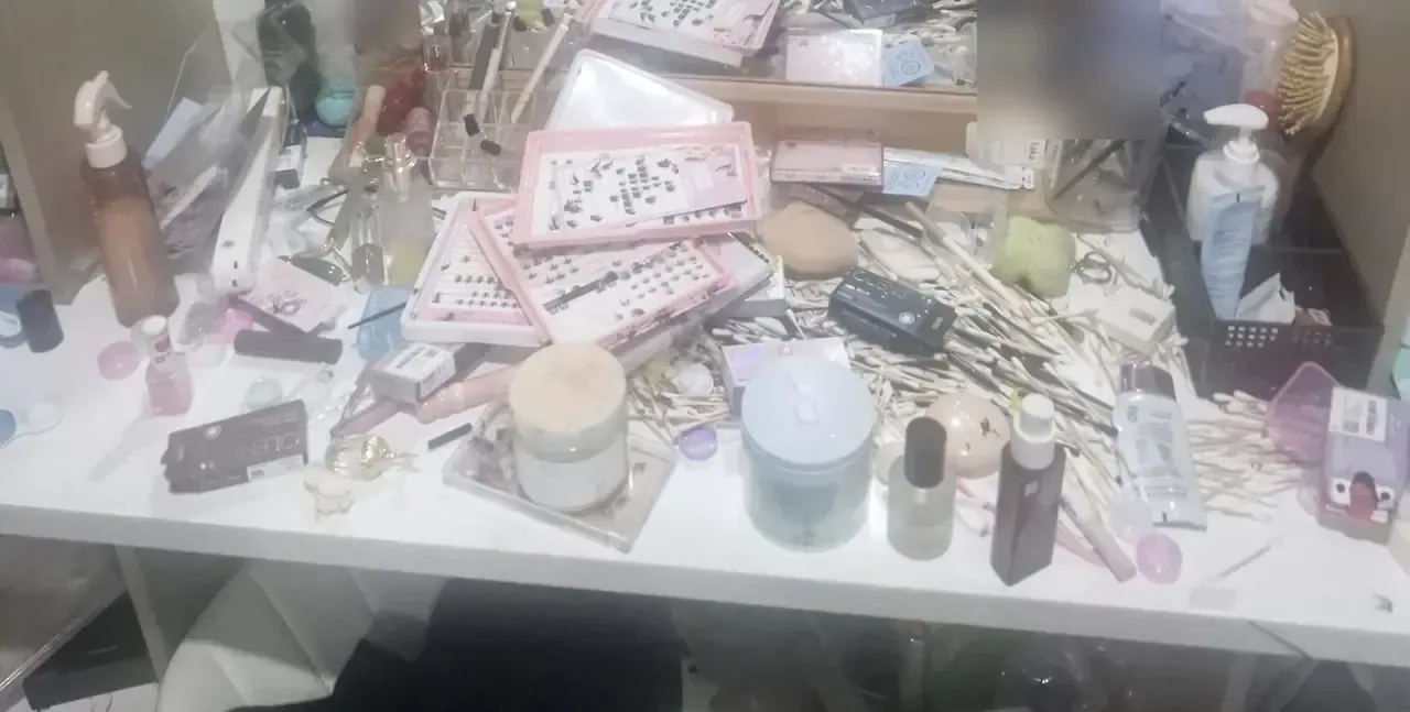 A dressing table completely covered in cosmetics, cotton buds, false lashes and packaging