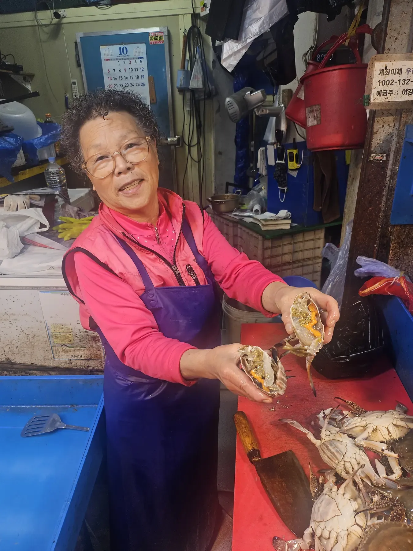 A market vendor holding open two crabs to show the roe inside