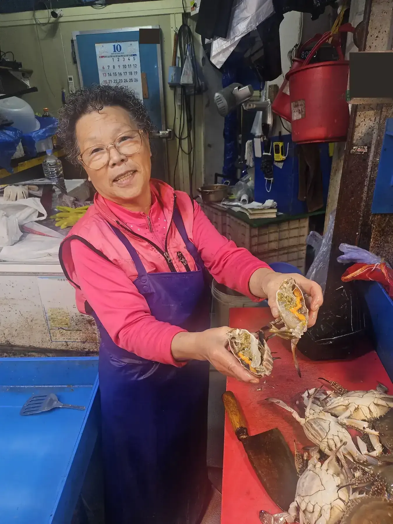A market vendor holding open two crabs to show the roe inside