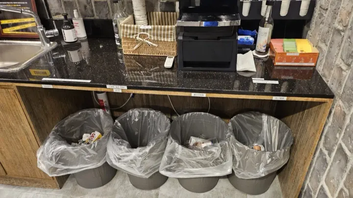 Four sorting bins in a row under a counter, labeled for general waste, paper, plastic, and cans