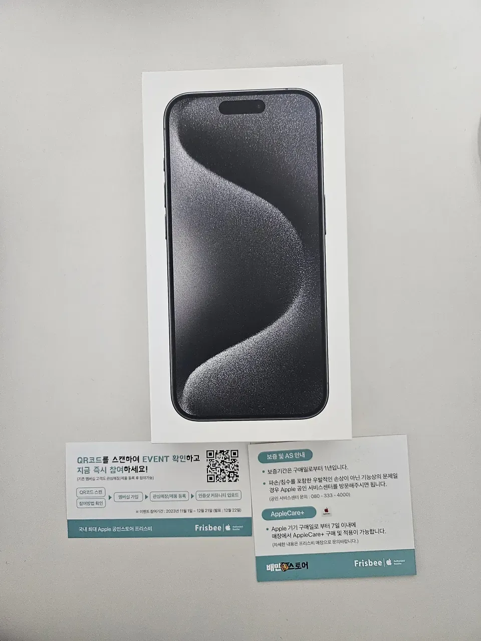 A sealed iPhone 15 Pro box with two reseller cards below it, one carrying the Baemin Store logo alongside the Apple authorised reseller mark