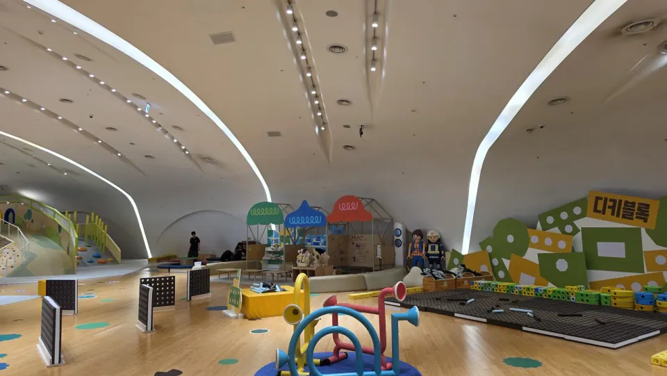 Inside a Seoul kids cafe: an indoor playground with a climbing wall, foam building blocks and a curved white ceiling