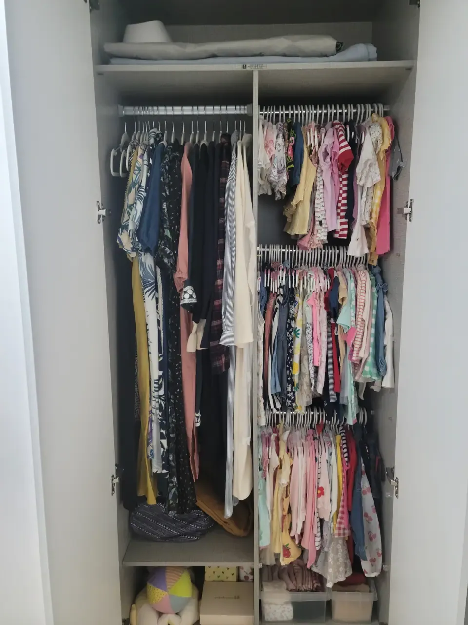 A wardrobe after organising, with children's clothes hung in size order and folded stacks below