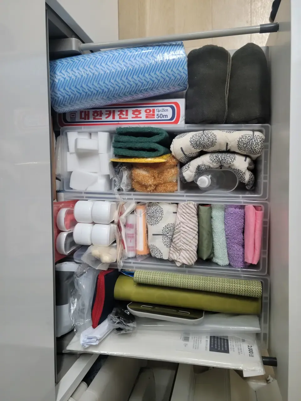 A kitchen drawer after organising, with cleaning supplies grouped into clear boxes