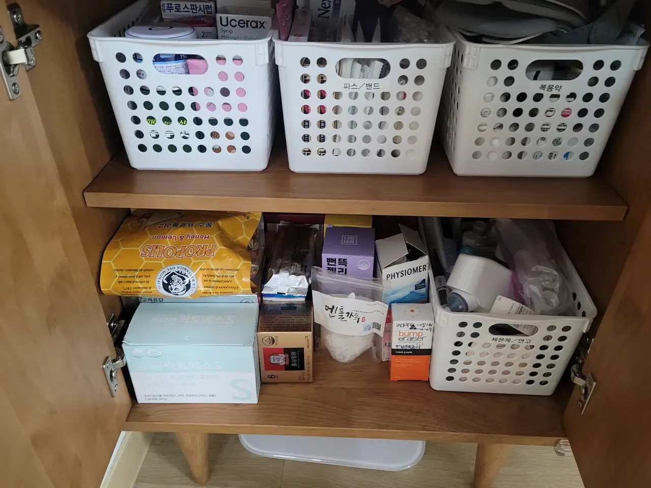 Three white baskets in a cabinet, each labelled in Korean for a different category of medicine