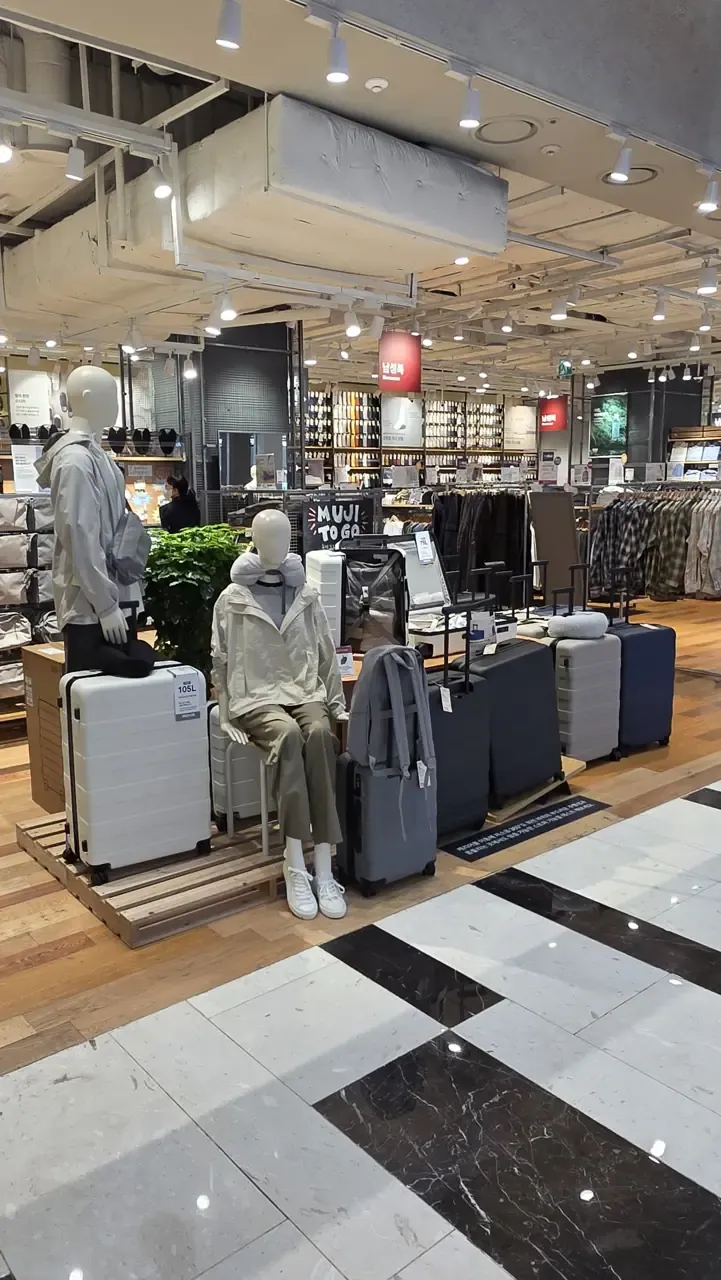 A MUJI TO GO display in IFC Mall with hard-shell suitcases in white, grey and navy, one labelled 105L