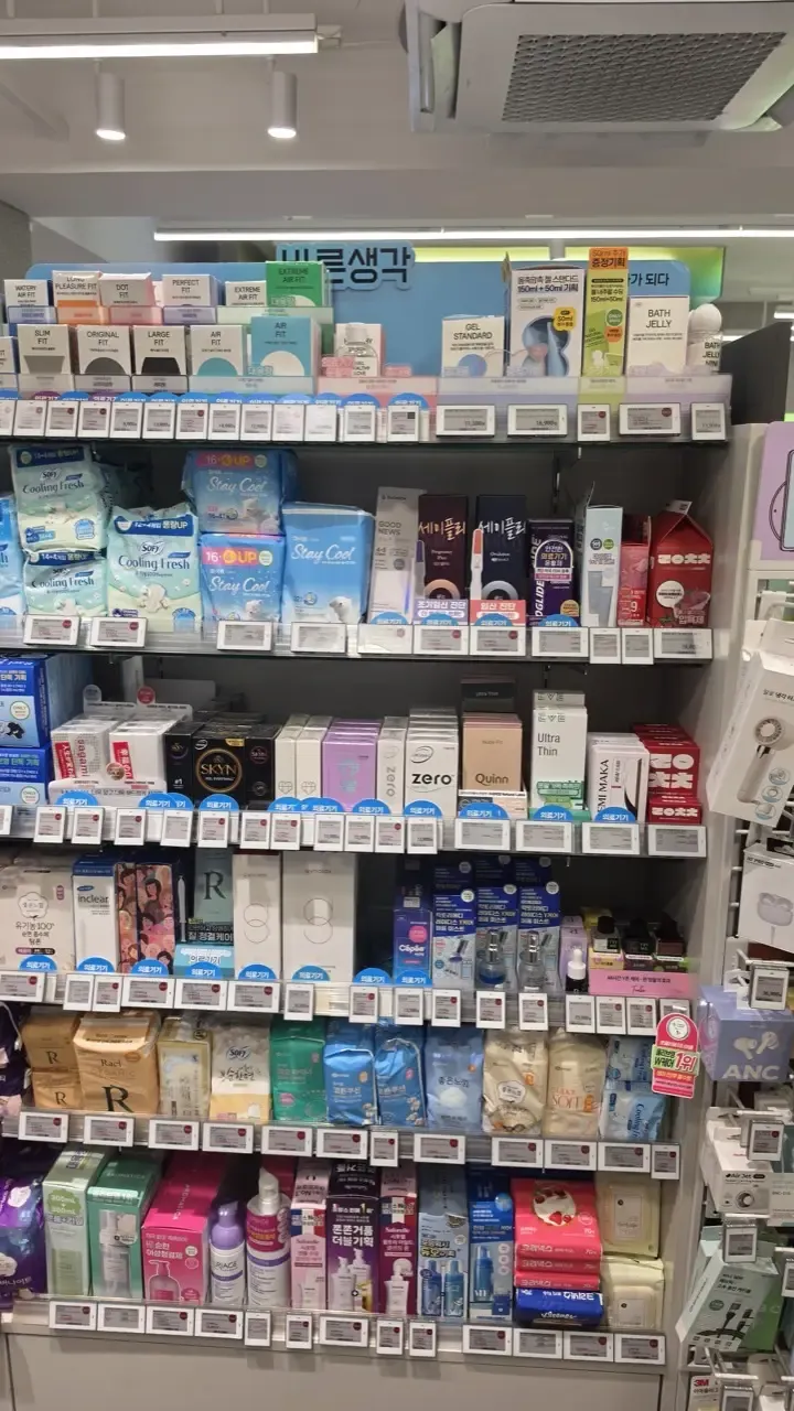 An Olive Young aisle stocked with condoms, lubricants, sanitary pads, panty liners and pregnancy tests side by side