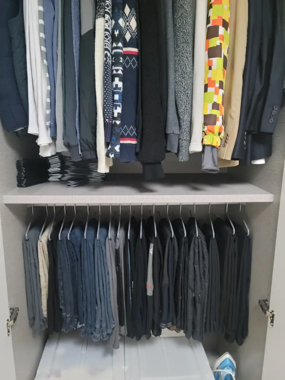 A Korean closet after a housekeeping visit — pants and jeans neatly folded over sliding hangers