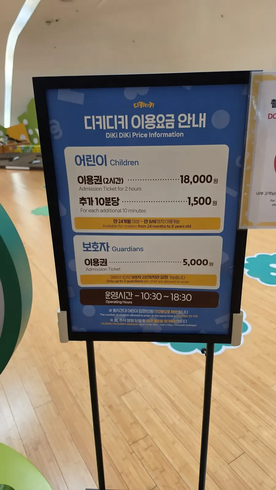 A bilingual price board at a Seoul kids cafe showing children's and guardians' admission rates