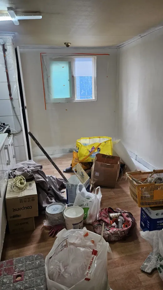 A room stripped back to bare walls during renovation, with paint tins and materials on the floor