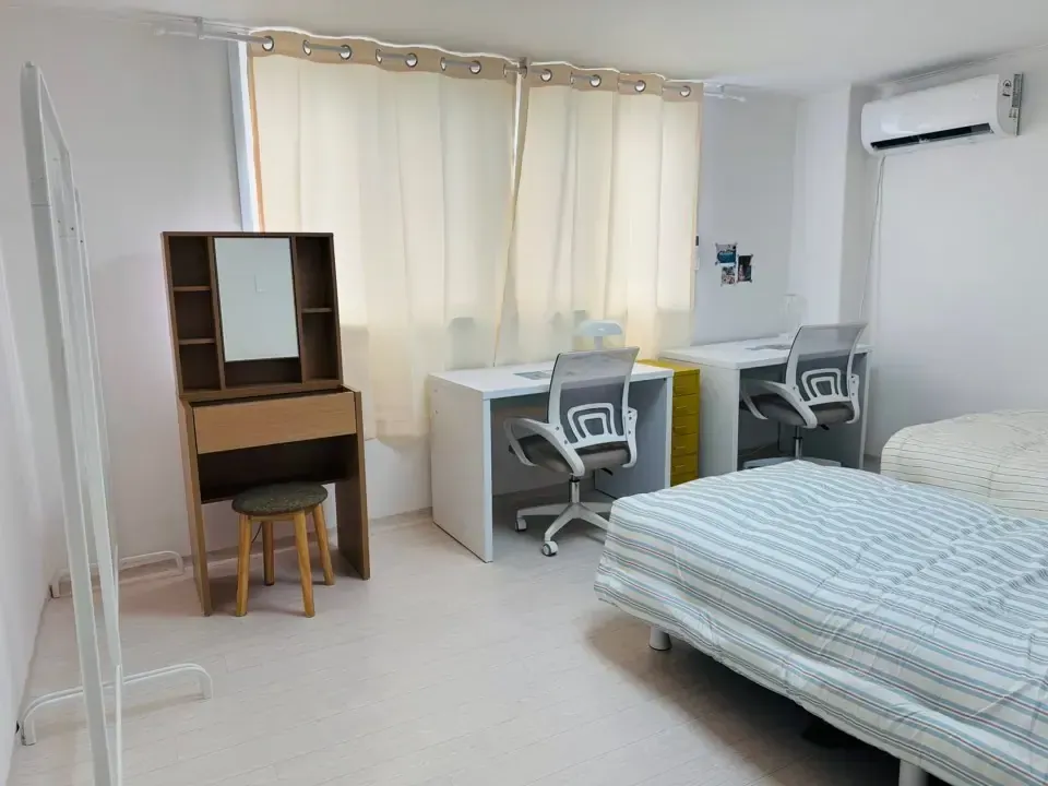 A twin room with two desks, two chairs, a dressing table and a bed