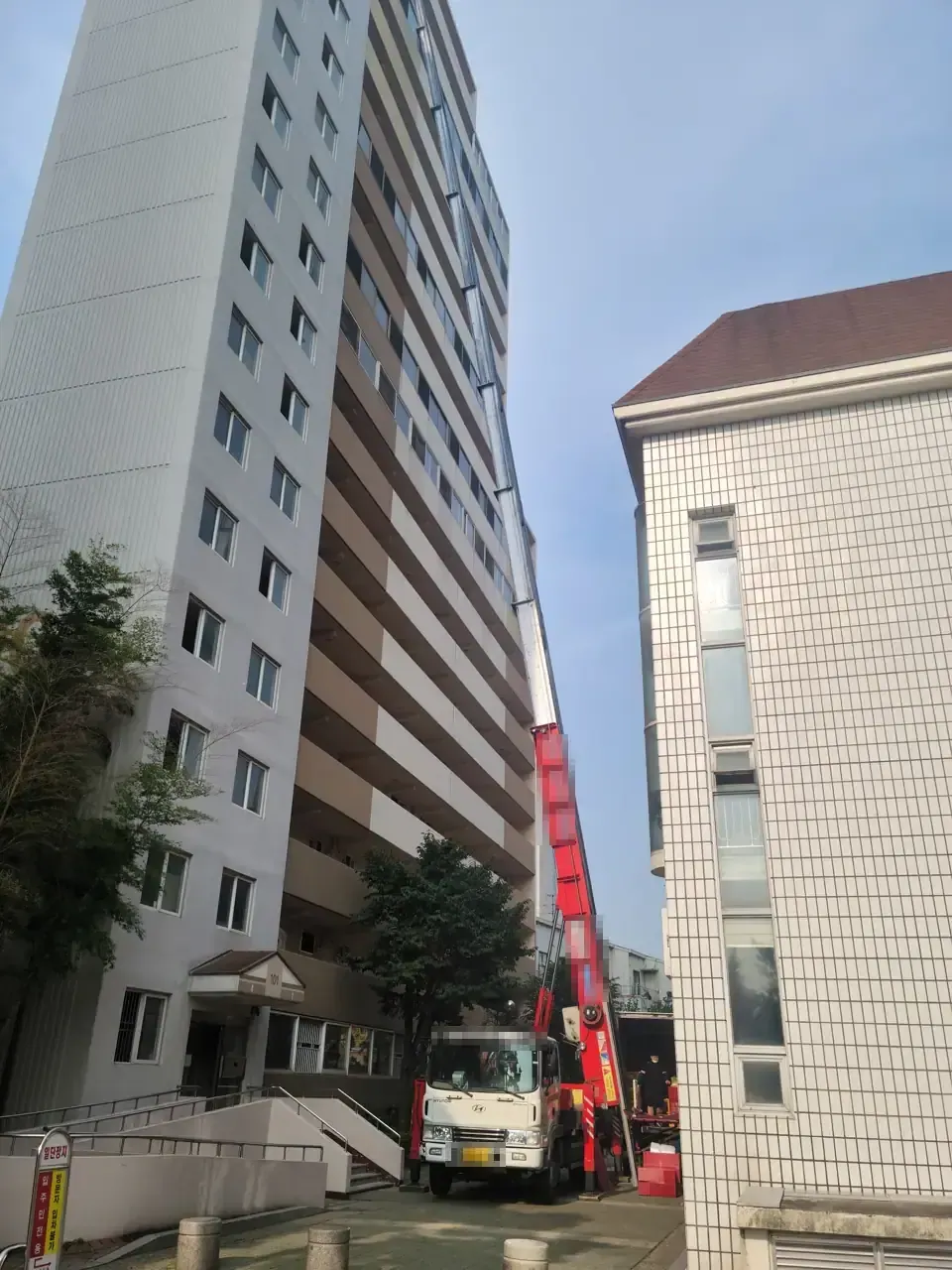 A red ladder truck extended to the upper floors of a Seoul apartment block