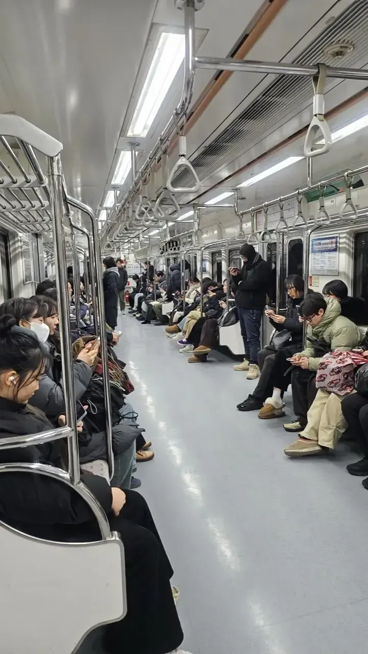The interior of a Seoul subway carriage with passengers seated along both sides