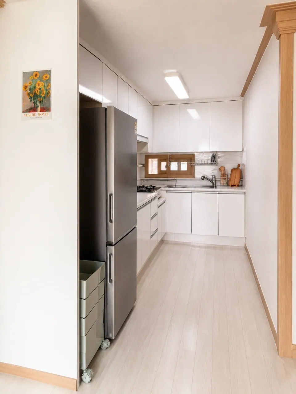 The galley kitchen: a tall fridge, gas hob, sink and white cabinets along one wall
