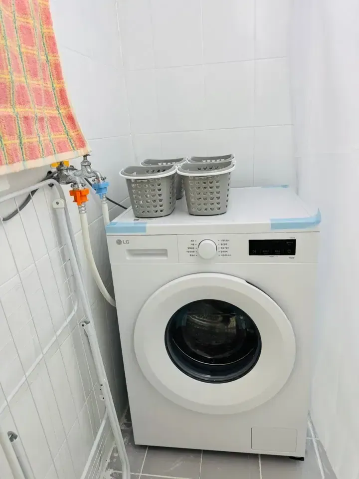 A washing machine with laundry baskets stacked on top and a drying rack beside it