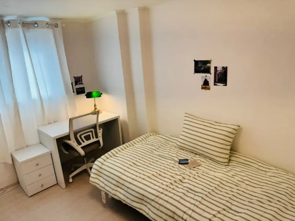 A furnished single room in a Seoul share house — bed, desk, chair, drawers and curtained window