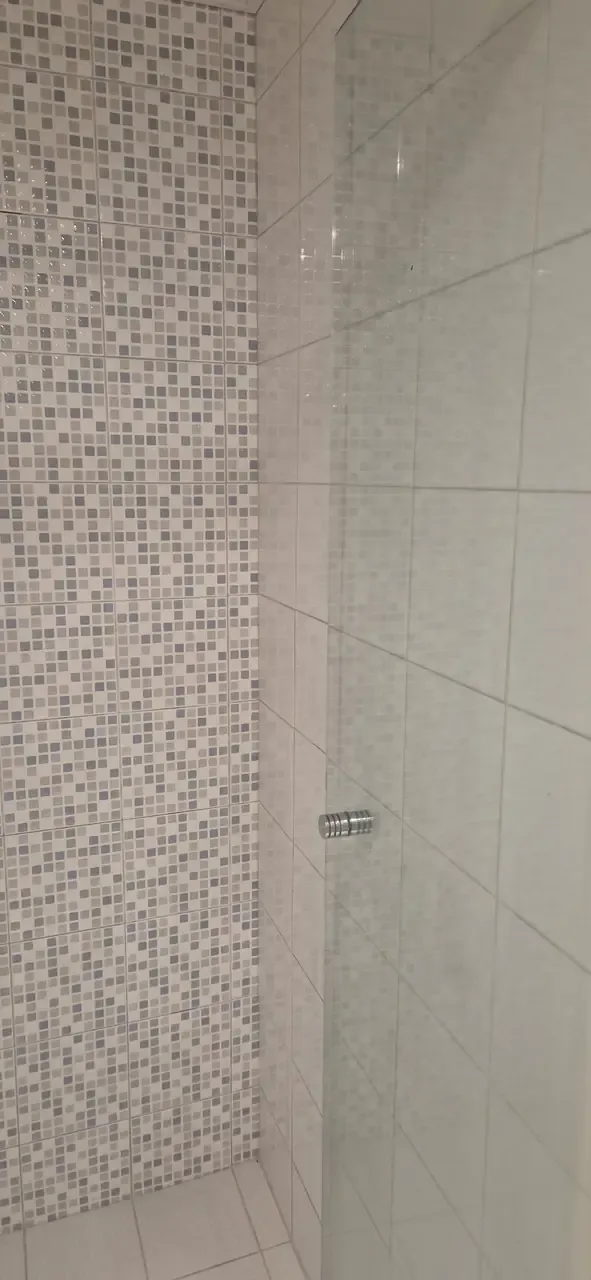 A cleaned shower corner, mosaic feature tiles beside plain white tiles and a glass screen