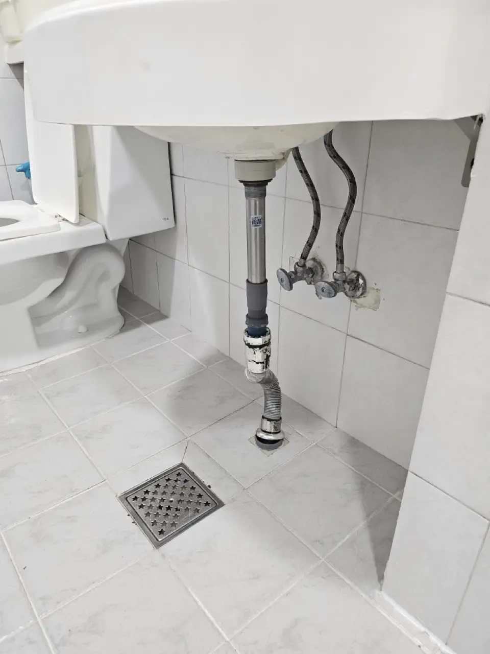 The flexible accordion pipe under a Korean bathroom sink, running from the basin to the floor drain