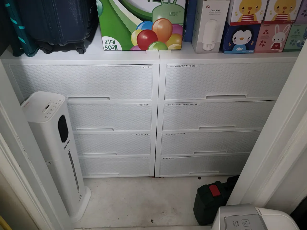 A wall of white plastic drawers in a storage room, each front carrying a printed Korean label