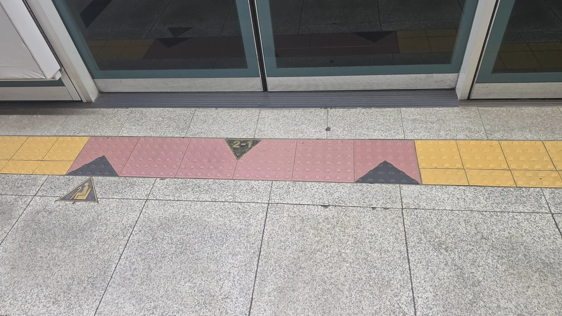 A Seoul subway platform floor marked 2-1 in front of the platform screen doors