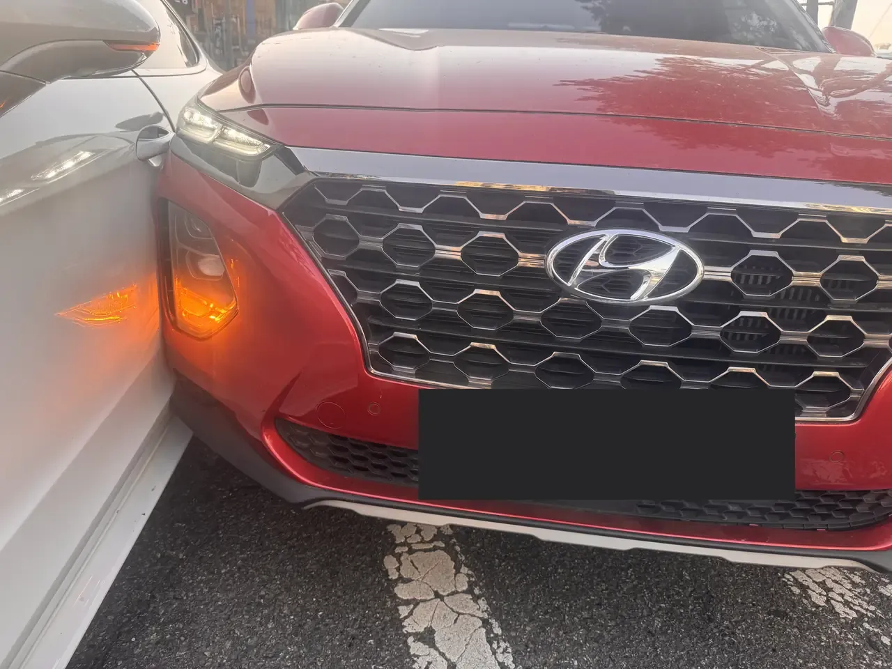 Close-up of a red SUV's front bumper pressed against the white bodywork of another car, licence plate obscured