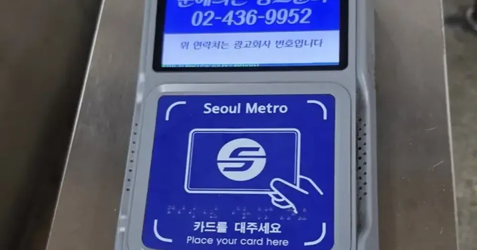 A Seoul Metro fare gate card reader with a blue panel reading 카드를 대주세요 and Place your card here