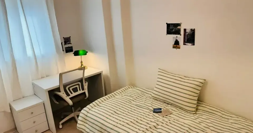 A small furnished one-room studio in Seoul with a bed, desk and curtained window