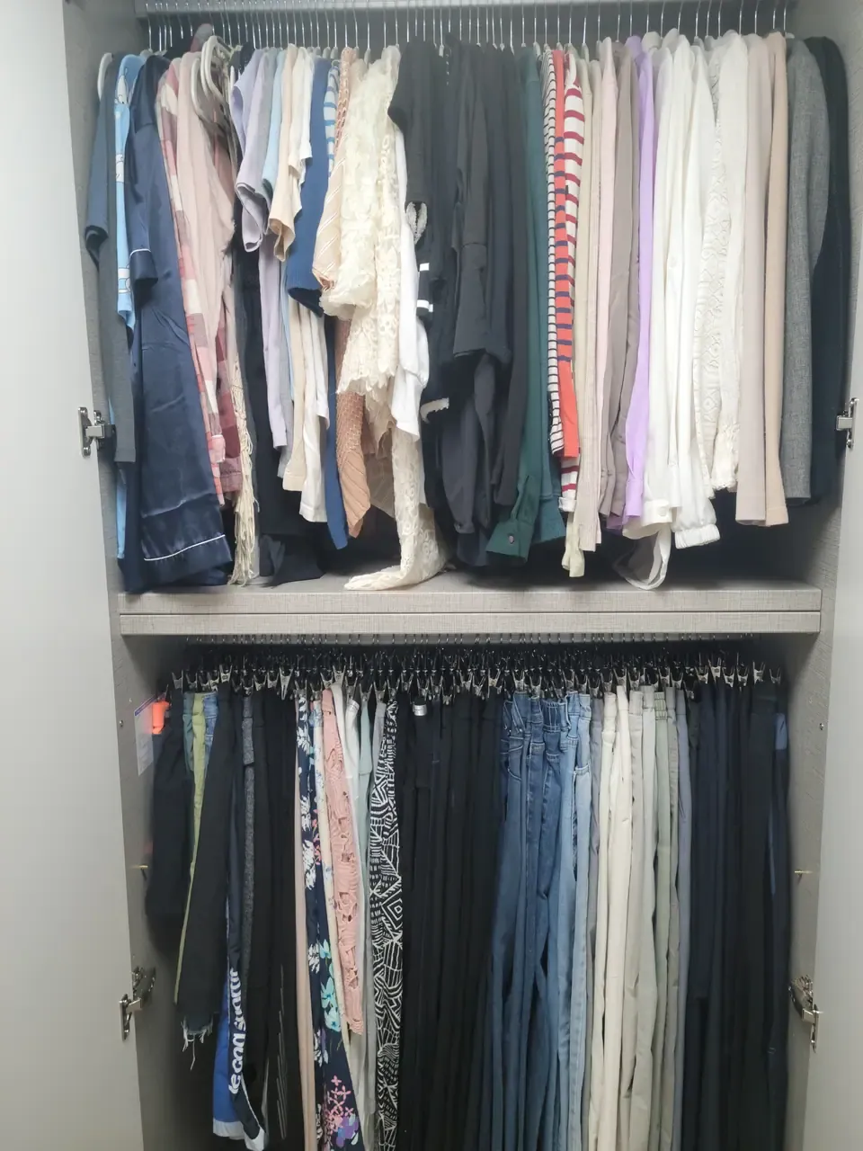 A Korean built-in wardrobe after organising, blouses folded in colour order on the left and trousers on clip hangers on the right