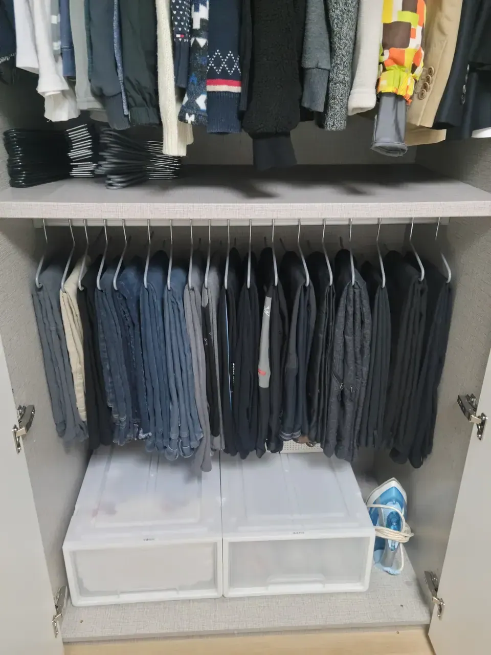 Trousers hanging in an even row on clip hangers in a Korean built-in wardrobe