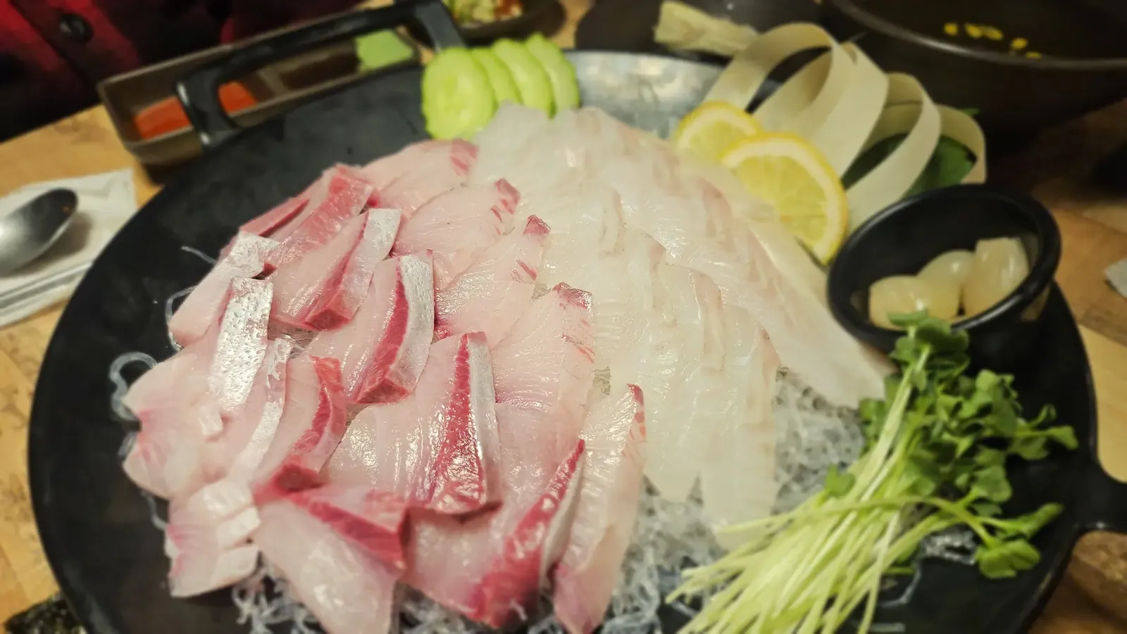 A platter of thick-cut yellowtail sashimi with a separate pile of white fish